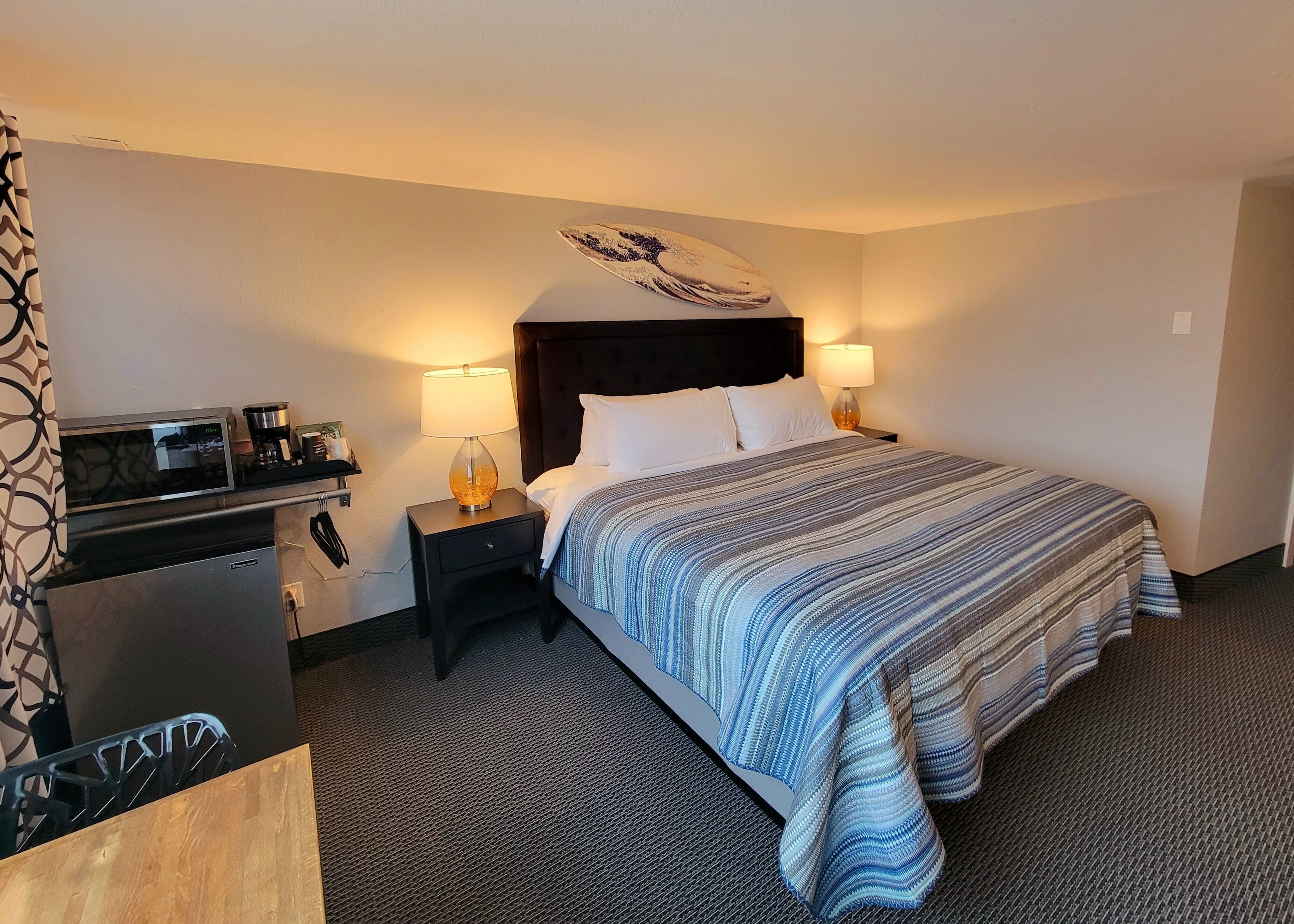 A hotel room with a bed, a desk with a computer, a microwave, and a coffee maker.