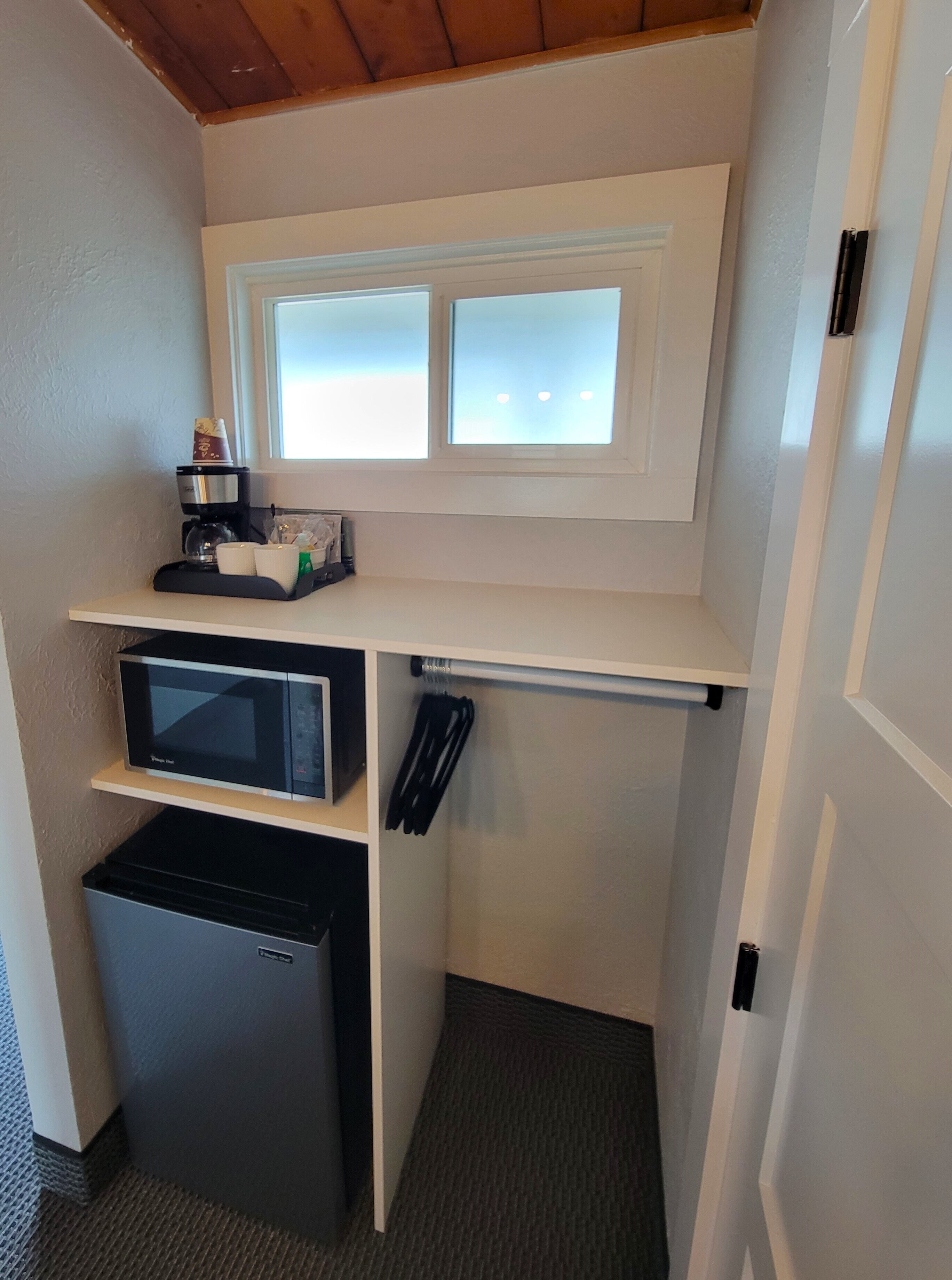 A compact kitchenette with a microwave, coffee maker, and small refrigerator.