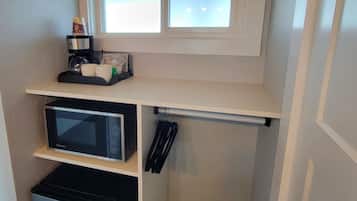 A compact kitchenette with a microwave, coffee maker, and small refrigerator.