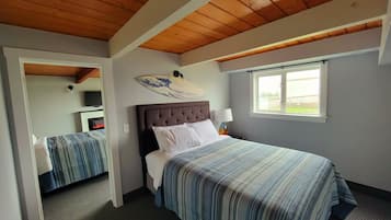 A bedroom with a large bed, a smaller bed, a window, and a wooden ceiling.