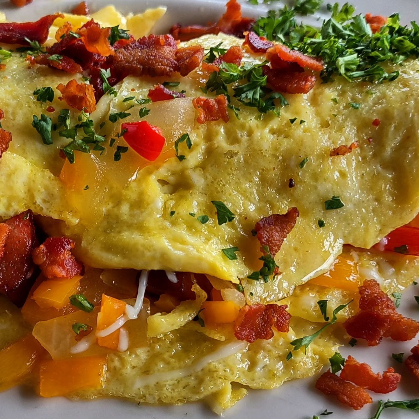A close-up of a breakfast dish with eggs, bacon, and diced vegetables.