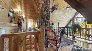 A wooden interior with a stone pillar, wooden railings, and a rocking chair.