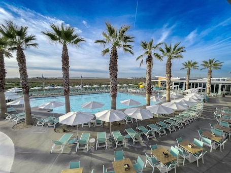 Una piscina al aire libre, camas de piscina con cargo, sombrillas