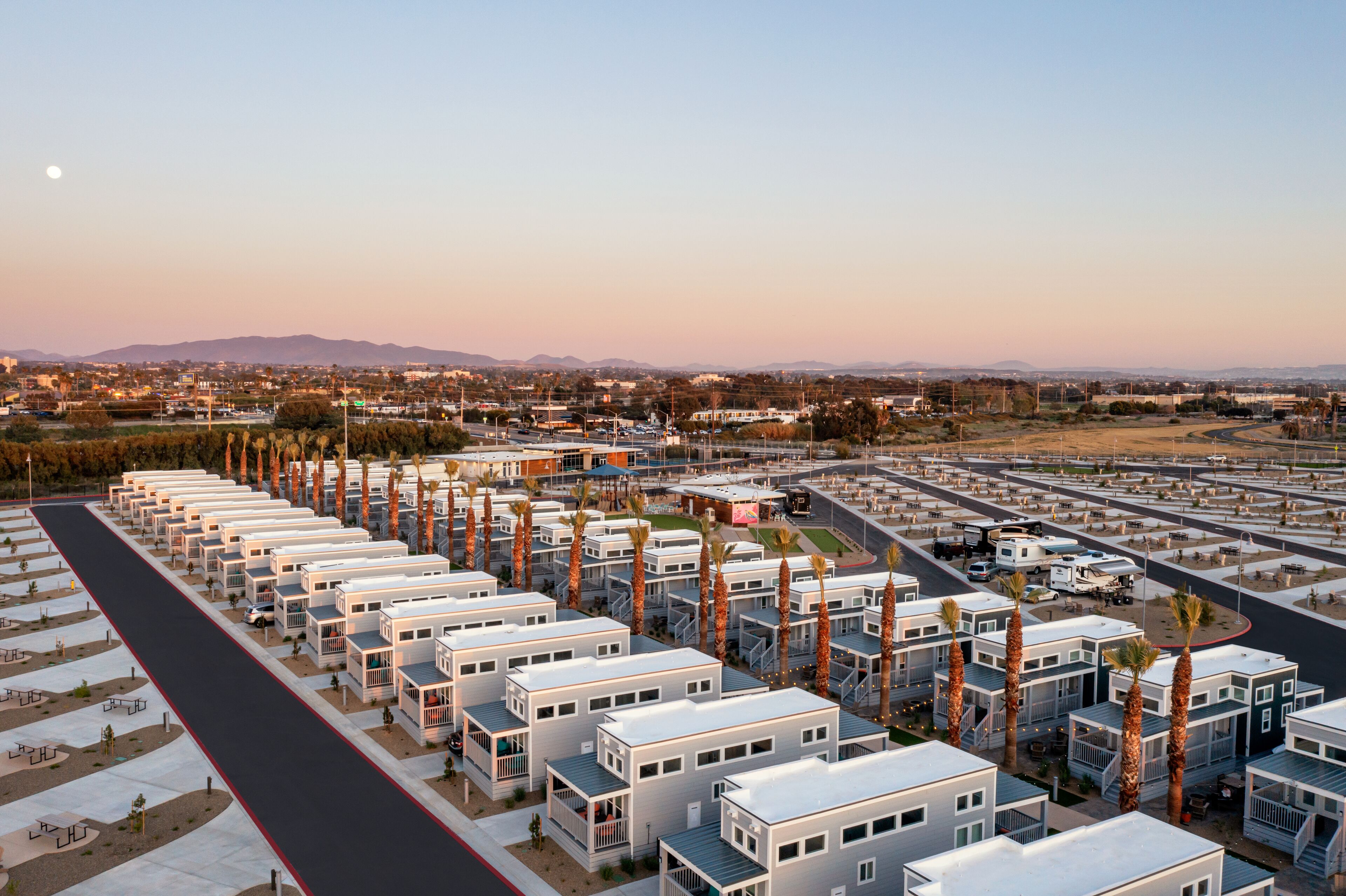 Una hilera de casas móviles modernas y compactas, con una calle central y zonas verdes circundantes.