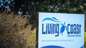 A sign for the Living Coast Discovery Center with a logo and text indicating its location in San Diego Bay, Chula Vista.