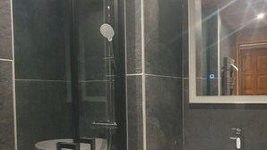 A modern bathroom with a glass-enclosed shower, a white sink, and a mirror above the sink. - Titre Provisoire (Montgenèvre)