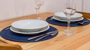 Una mesa de comedor dispuesta con platos, cubiertos y copas de vino.