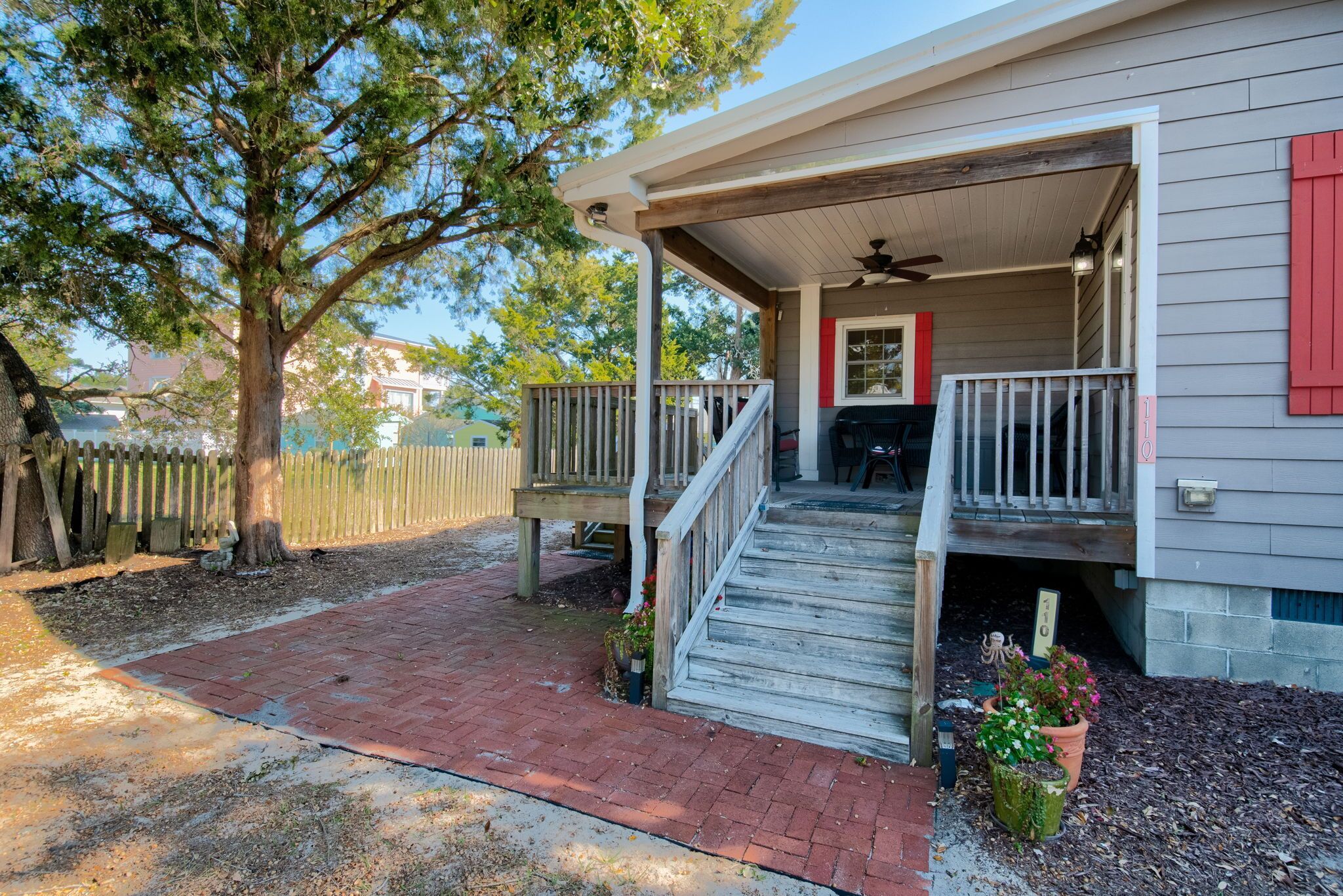 A house with a covered porch, a wooden deck, and a brick pathway leading to the entrance.