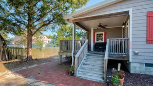 A house with a covered porch, a wooden deck, and a brick pathway leading to the entrance. - Bungalow on 5th (Kure Beach)