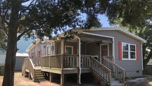 A single-story house with a porch, a staircase, and a small deck. - Bungalow on 5th (Kure Beach)