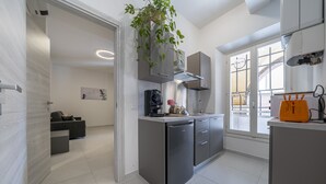 A modern kitchen with a built-in dishwasher, a coffee machine, and a plant. There is a window with a view of the outside. - [rua Muro] Piano Nobile Family (Modena)