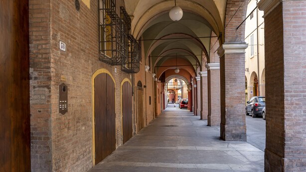 A brick corridor with arched ceilings and a row of doors on one side. - [rua Muro] Piano Nobile Family (Modena)