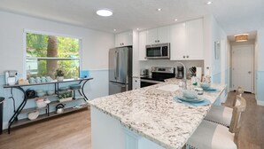 Una cocina moderna con armarios blancos, electrodomésticos de acero inoxidable y encimera de mármol.