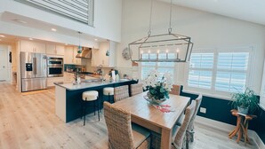 A spacious kitchen with a central island, stainless steel appliances, and a hanging light fixture.