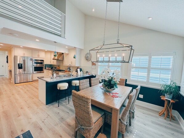 A spacious kitchen with a central island, stainless steel appliances, and a hanging light fixture.