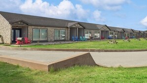 A row of motel-style buildings with individual rooms, each featuring a porch and outdoor seating.