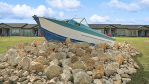 A boat resting on a pile of rocks in front of a row of hotel buildings. - MotorBoat Inn Suite 1 Pet Friendly (Graford)