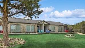 A stone house with a covered porch, a lawn, and a picnic table. - MotorBoat Inn Suite 1 Pet Friendly (Graford)