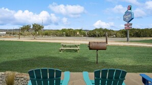 A grassy area with two green chairs, a picnic table, and a mailbox. In the background, there is a sign for a motel. - MotorBoat Inn Suite 1 Pet Friendly (Graford)