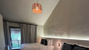 Un dormitorio con dos camas, una lámpara colgante, suelo de piedra y vistas al exterior a través de una ventana.