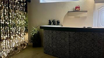 Un espace d’accueil avec un comptoir décoré, un mur orné d’objets suspendus et une petite plante.