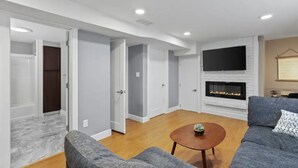 A modern living room with a fireplace, grey sofas, and a wooden coffee table. - Exquisite Comfort: Luxury Suite (Portland)