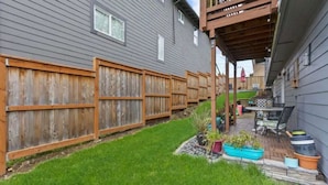 A backyard with a wooden fence, a patio with a table and chairs, and potted plants. - Exquisite Comfort: Luxury Suite (Portland)