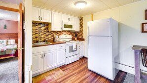 Une cuisine de taille réduite avec des meubles blancs, un four à micro-ondes, une cuisinière et un réfrigérateur.