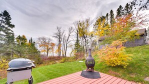 Une terrasse en bois rouge avec un barbecue et un vase décoratif.