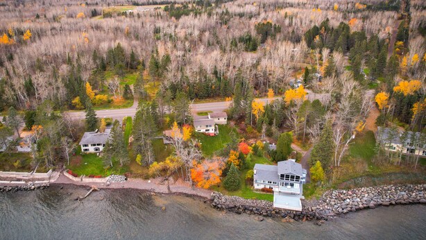 Un quartier résidentiel où les maisons sont entourées de forêt et bordées par un plan d’eau.