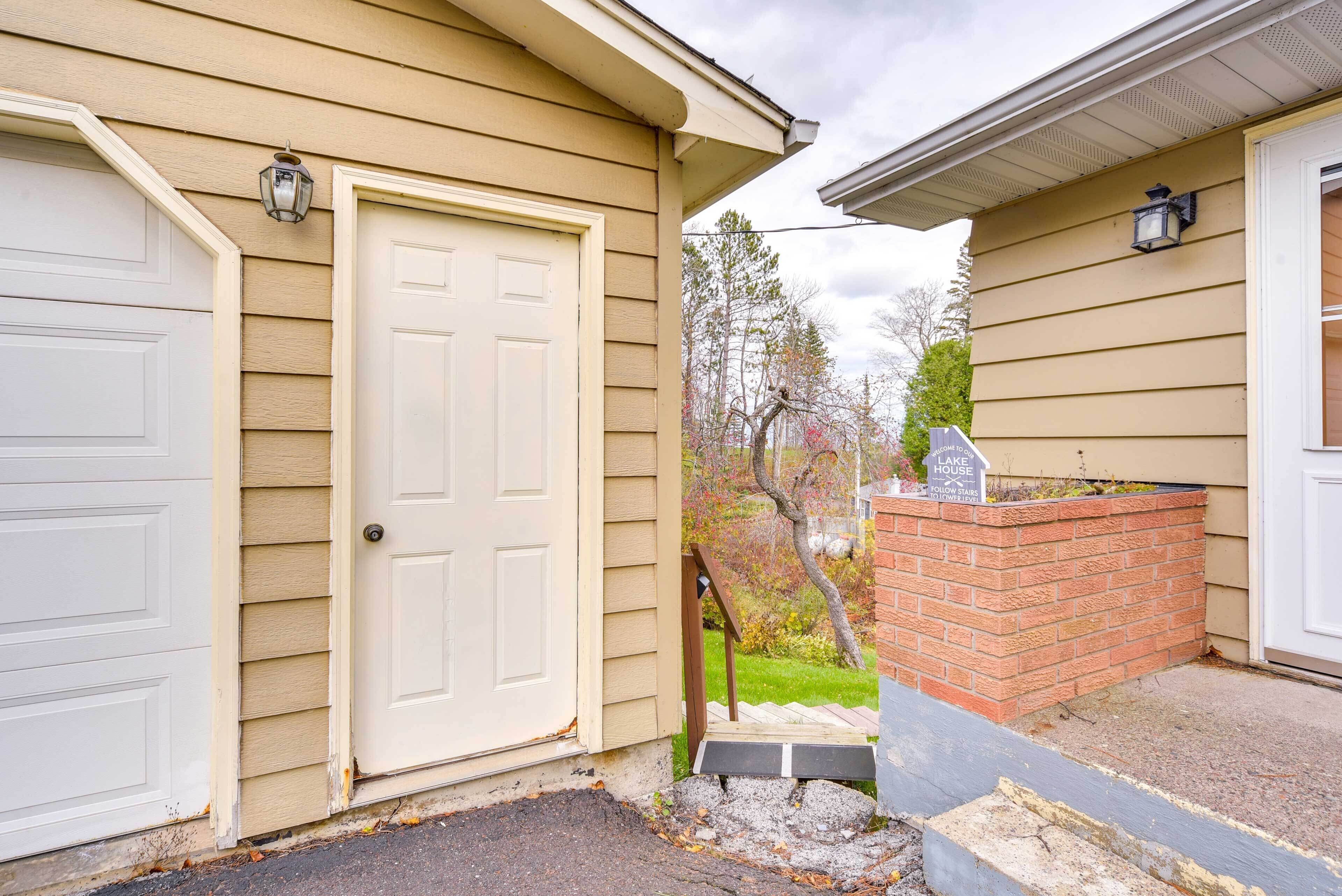A house with a beige exterior, a white garage door, and a brick planter with a sign.