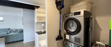A laundry area with a washing machine, dryer, and a vacuum cleaner.