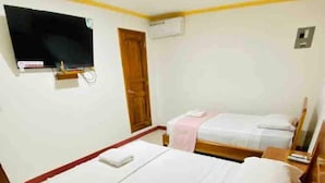 A hotel room with two beds, a TV mounted on the wall, and a wooden door.