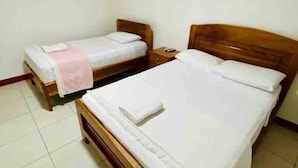 A room with two wooden beds, white bedding, and a tiled floor.