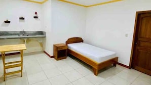 A bedroom with a bed, bedside table, and a small desk.