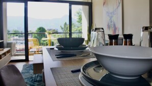 Un comedor con vista a las montañas, una mesa con platos y cubiertos, y una silla.
