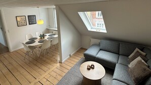 A modern loft apartment with a dining area, a gray sofa, and a skylight. - Modern apartment for 6 in city center (Aalborg)
