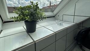 A potted plant on a tiled balcony with a clear view of a church spire in the background. - Modern apartment for 6 in city center (Aalborg)