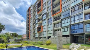 Un bâtiment moderne doté d’une piscine, de balcons et de grandes fenêtres.