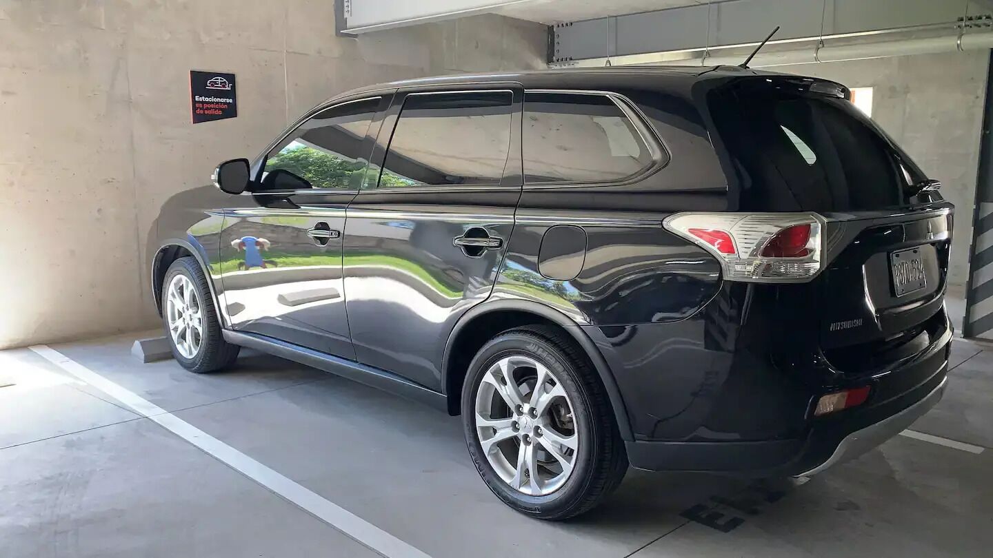 A black SUV parked in a garage with a concrete floor and a wall with a sign.