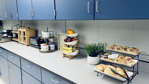 Une cuisine avec des meubles de rangement bleus, une machine à café, un grille-pain et un panier à fruits.