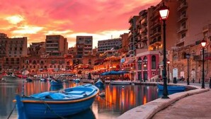 Une vue urbaine sur le front de mer, avec des bateaux amarrés, des bâtiments et une rue bordée de boutiques.