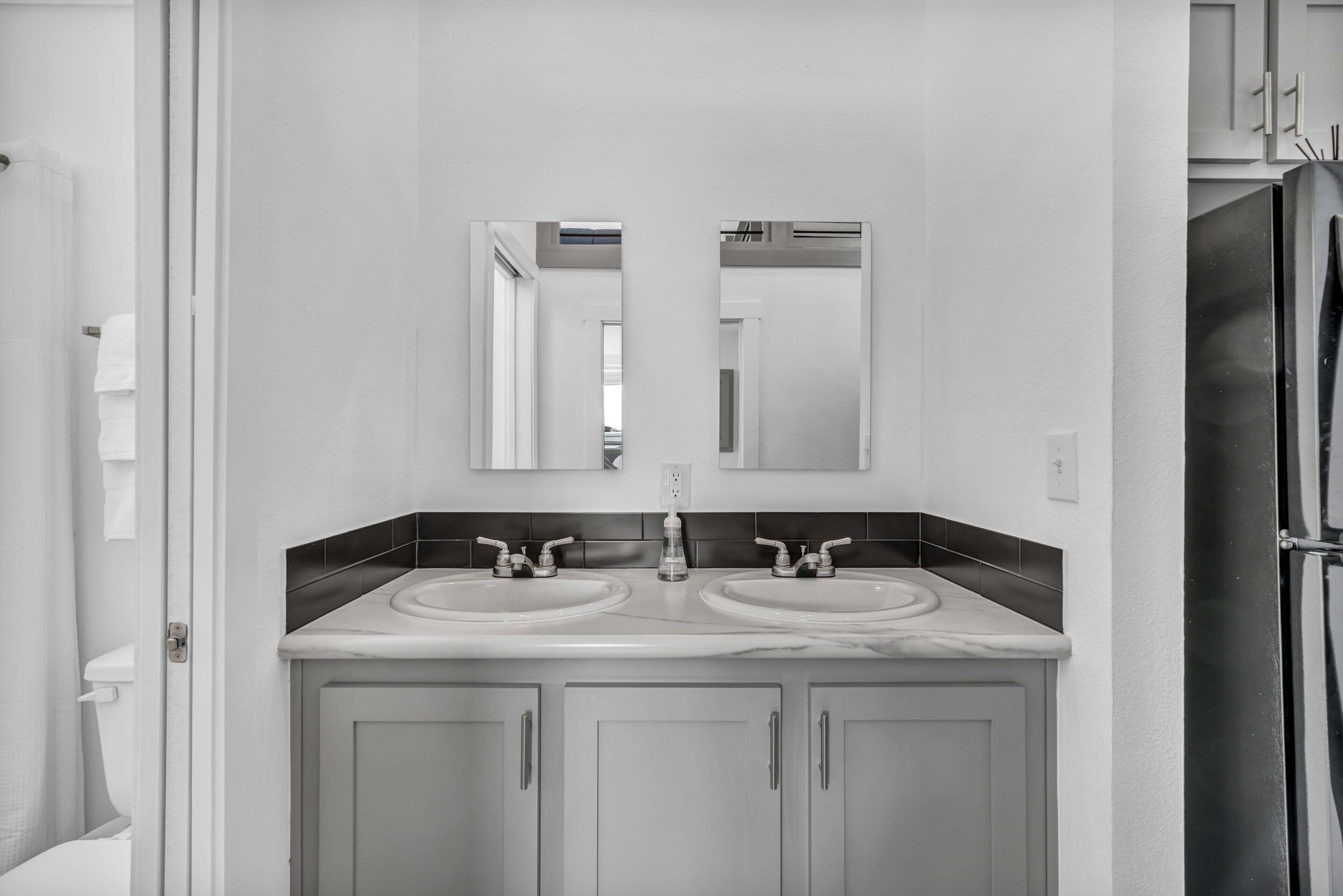 A bathroom with two sinks, a mirror above, and cabinets below.