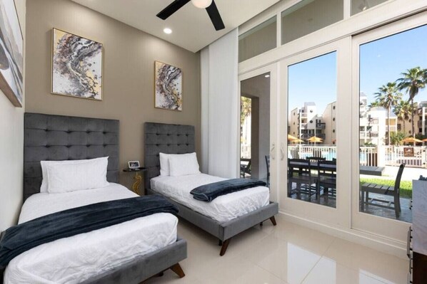 A hotel room with two beds, a large sliding glass door leading to a balcony, and artwork on the walls.
