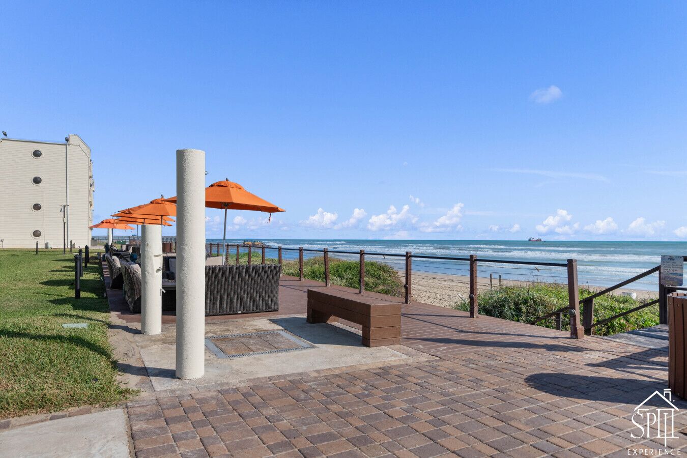 Eine Terrasse am Strand mit Sitzgelegenheiten im Freien, einer Holzbank und Blick auf das Meer.