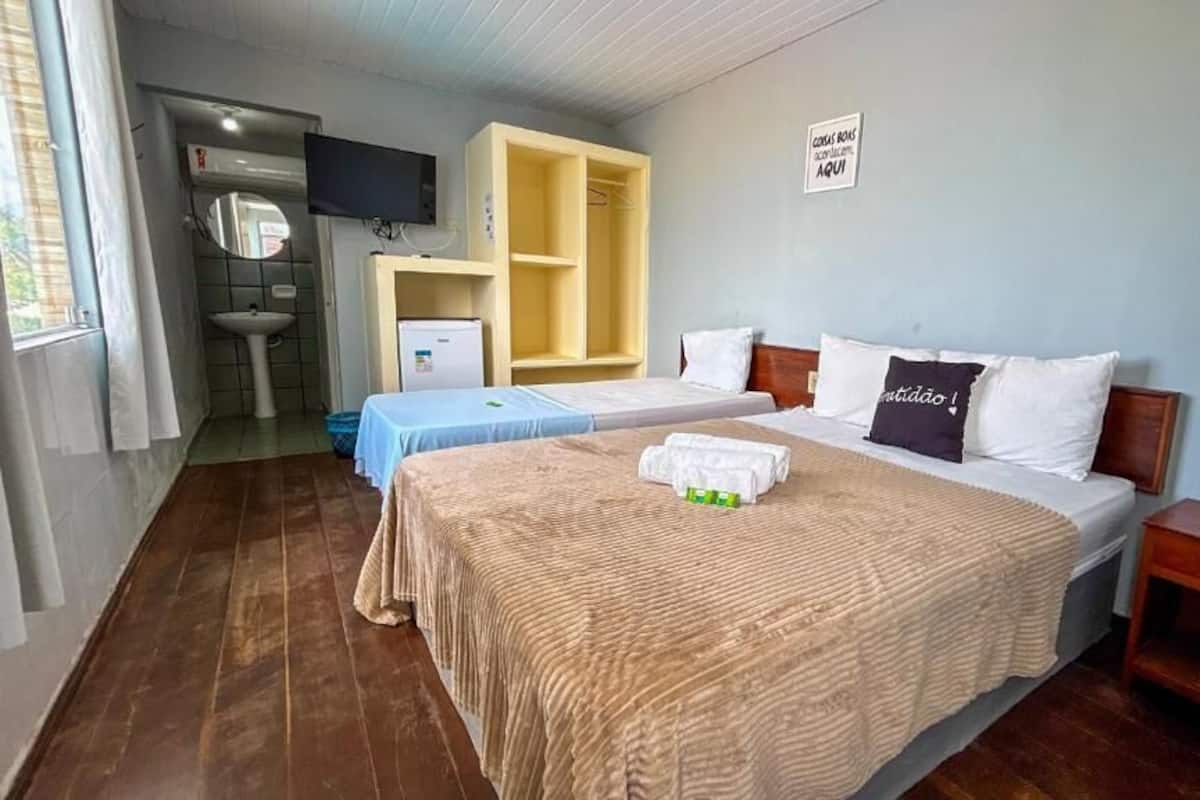 Une chambre d’hôtel avec deux lits, une télévision, une armoire et un lavabo.