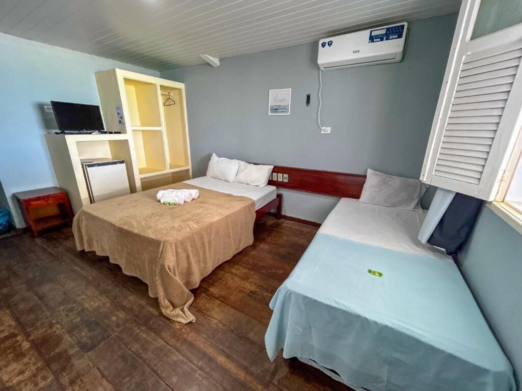 Een kamer met twee bedden, een kledingkast, een televisietoestel en airconditioning.
