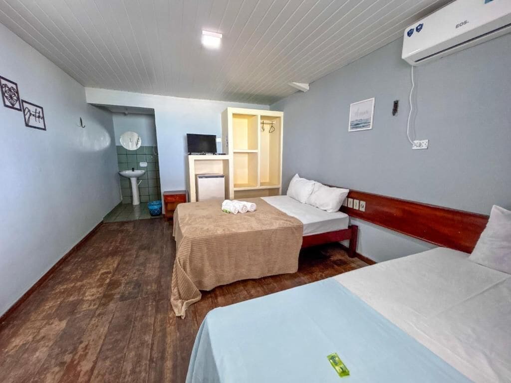 A hotel room with two beds, a small kitchenette, a sink, and a television.