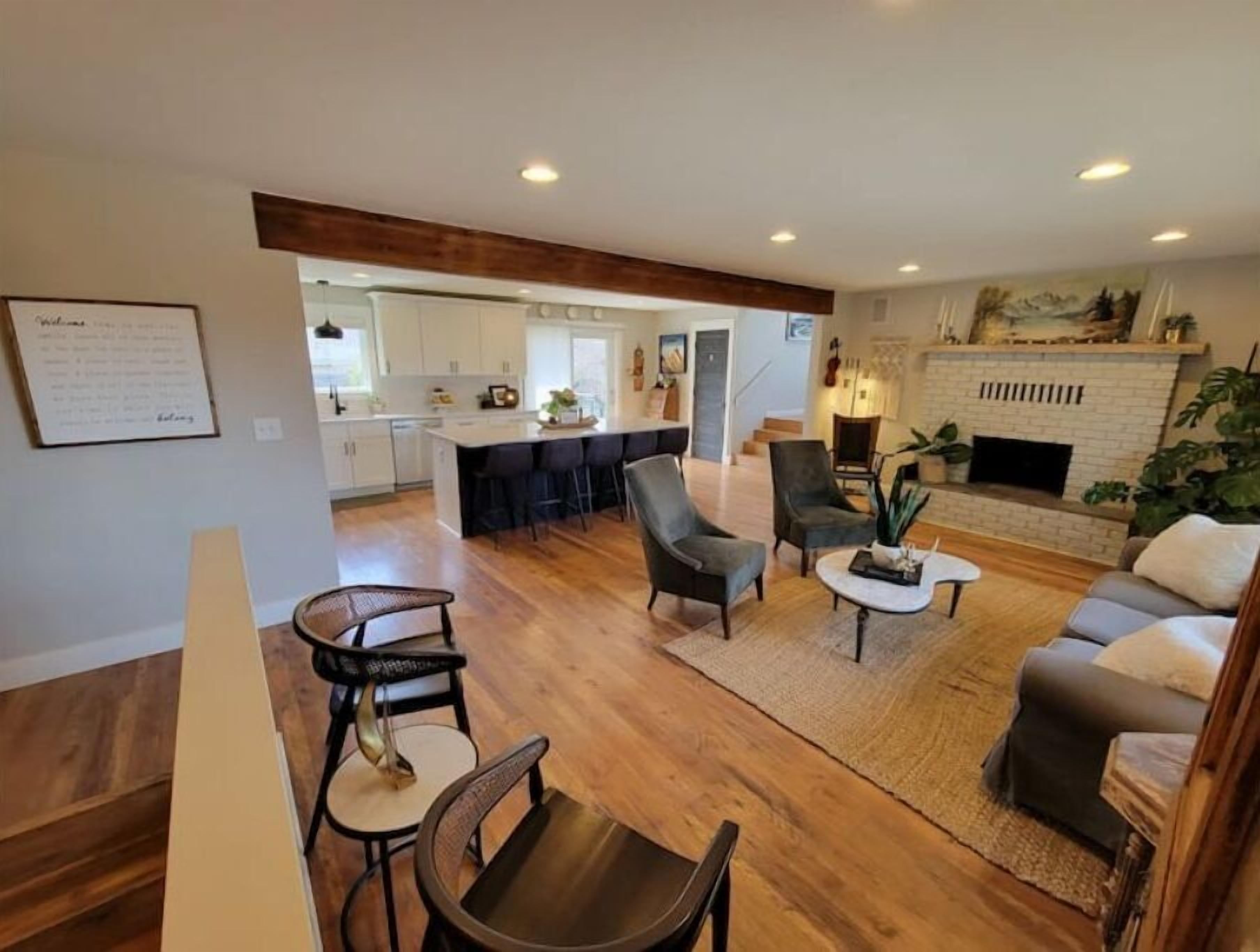A spacious living area with a fireplace, a dining area with a bar, and a kitchen with white cabinets.