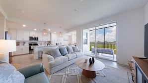 A modern kitchen with white cabinets, a microwave, and a dining area with a round wooden table. - Ave Maria - Relax & Golf. Golf resort with great amenities and gorgeous views. (Ave Maria)